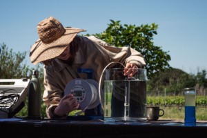 Une jeune femme trempe une sonde dans un bocal d'eau salée pour démontrer le gradient de salinité existant dans le sous-sol de la Camargue.